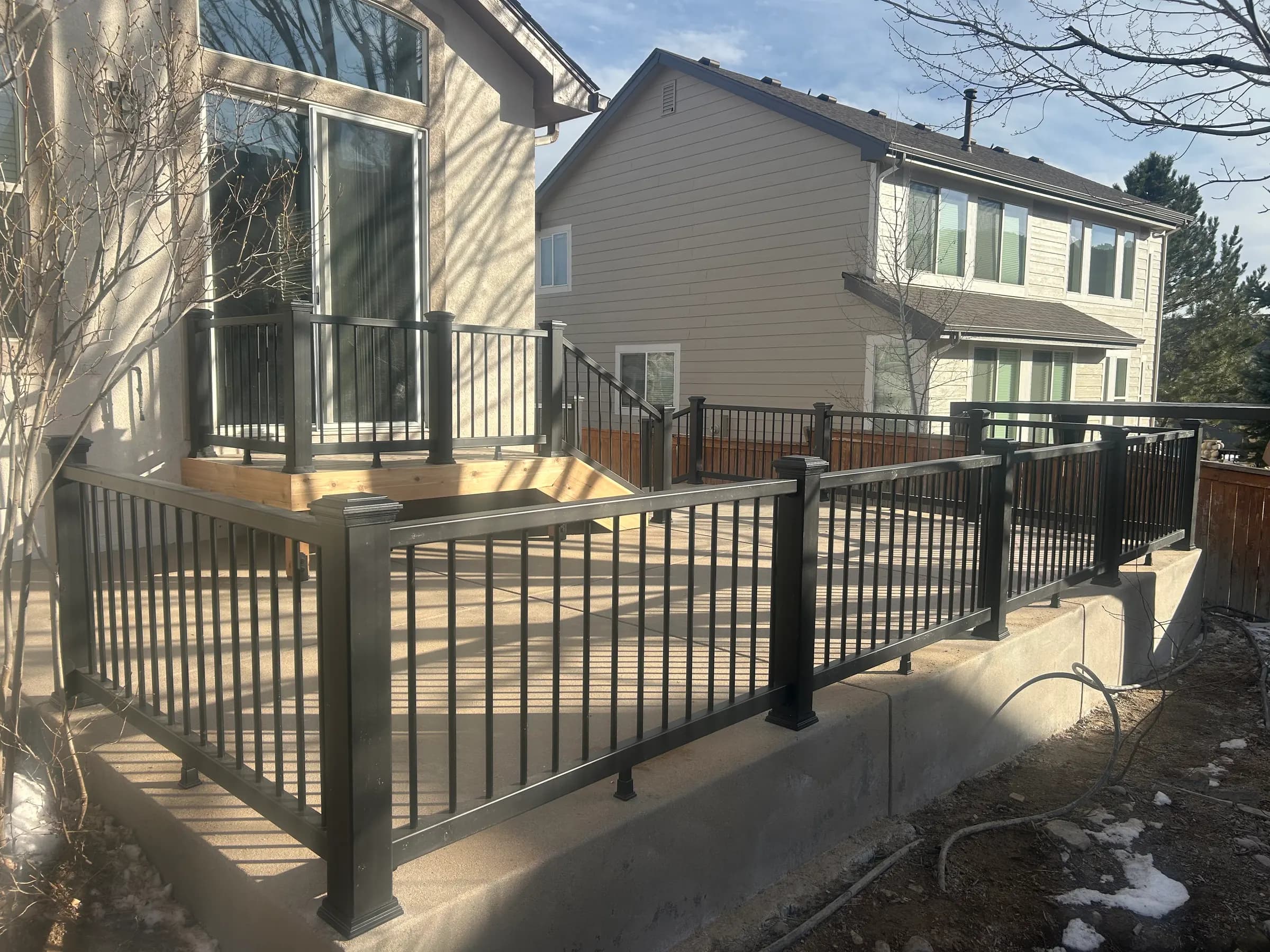 Black aluminum railing along a raised concrete patio