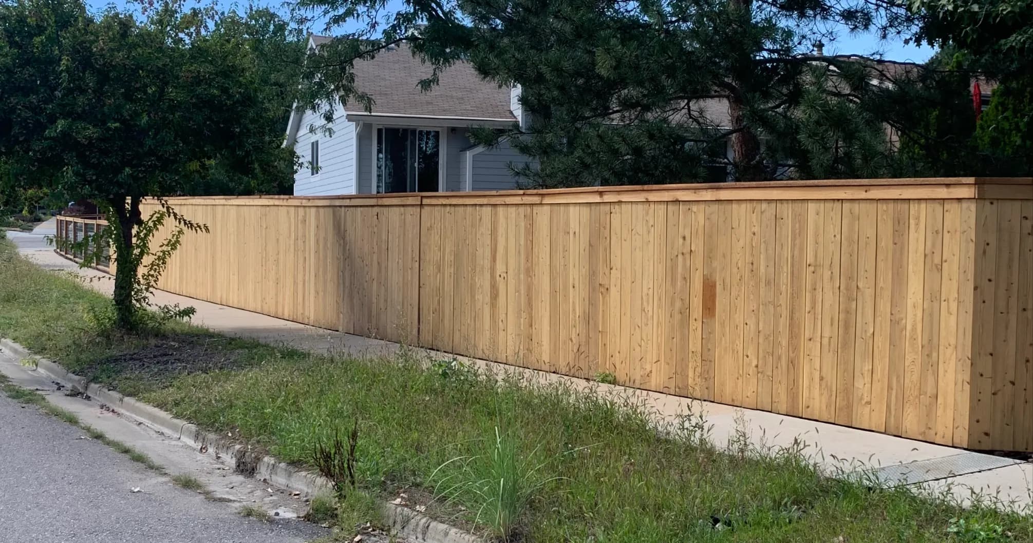 Long cedar privacy fence along a residential sidewalk