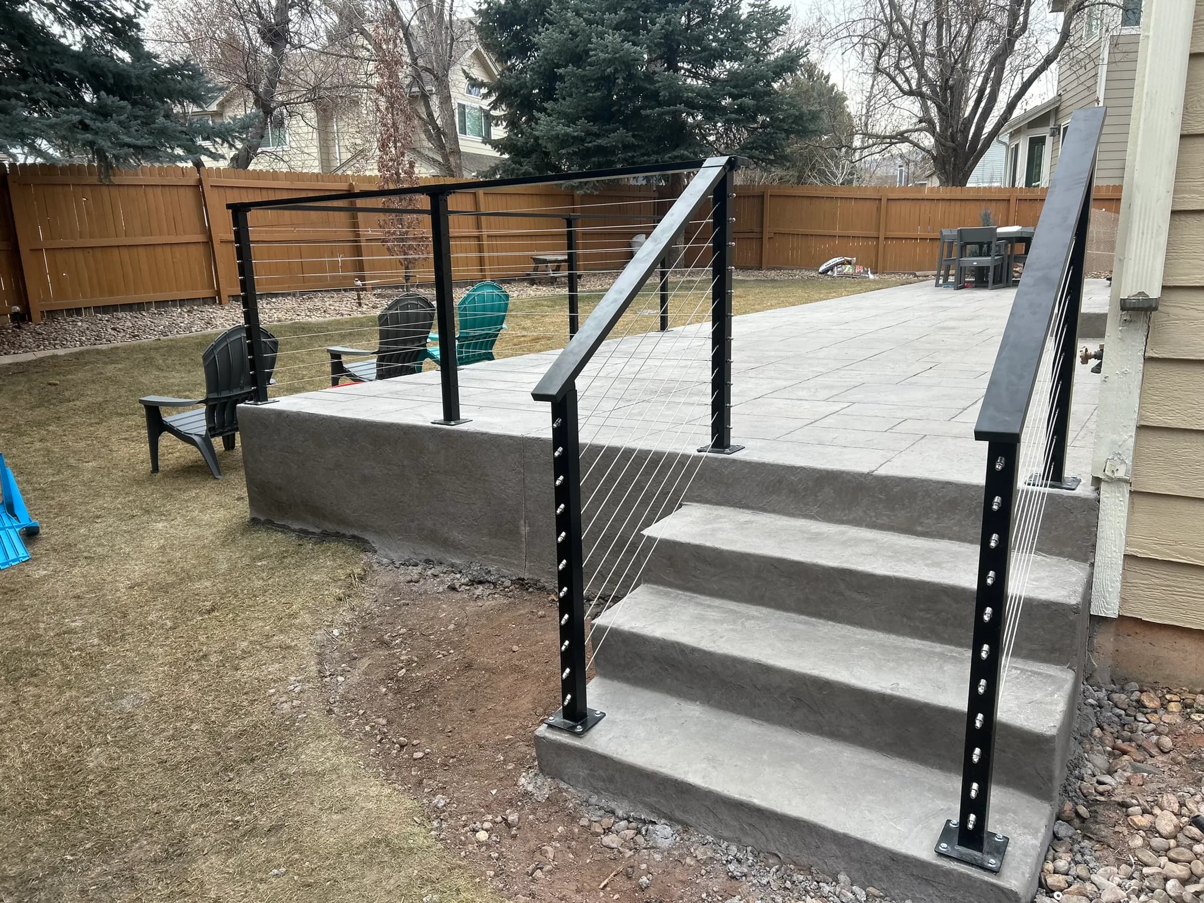 Raised concrete patio with steps and black cable railing